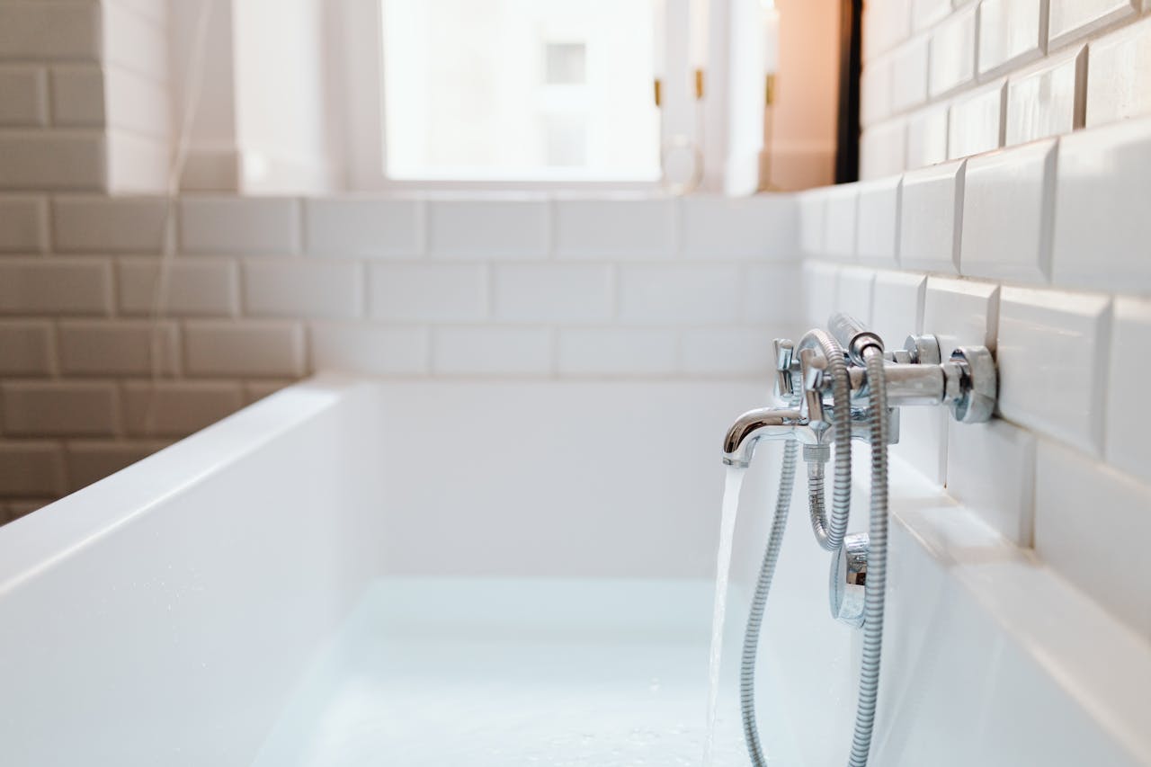 Stylish ceramic bathtub with modern stainless steel faucet in a sunlit bathroom. Modern bathtub and faucet in a sunlit bathroom – Villa Plumbing provides expert plumbing services in the East Bay.